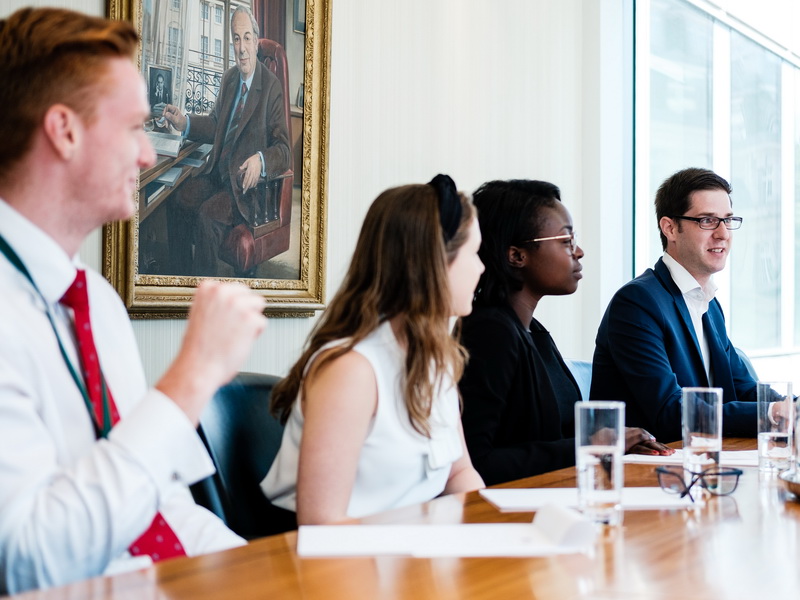 Team discussing a client in front of a painting of our founder